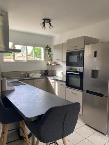une cuisine avec une table et un réfrigérateur dans l'établissement Maison au calme à 900m du bourg, à Carcans