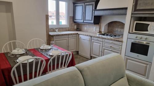une cuisine avec une table et des chaises ainsi qu'une cuisine avec une cuisinière dans l'établissement Appartement Corte centre ville, à Corte