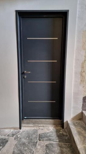 une porte noire dans une pièce avec un sol en pierre dans l'établissement Appartement Corte centre ville, à Corte