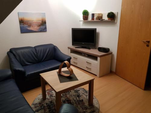 a living room with a couch and a tv and a table at Ferienwohnung Schwalbennest in Carolinensiel