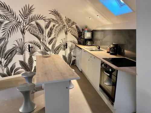 - une cuisine avec des placards blancs et un papier peint tropical dans l'établissement Chambre dans colocation Cholet Centre, à Cholet