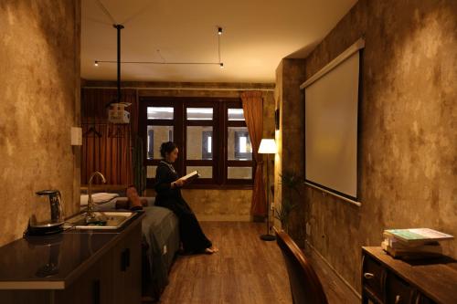 a woman sitting on a bed reading a book in a room at Mustang 11-11 Boutique Hotel Self Check In in Ho Chi Minh City