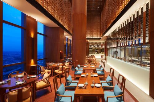 a restaurant with tables and chairs and large windows at Hyatt Regency Shanghai Jiading in Jiading