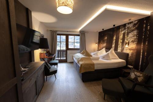 a hotel room with a large bed and a television at Boutique Hotel Mandarfnerhof in Sankt Leonhard im Pitztal