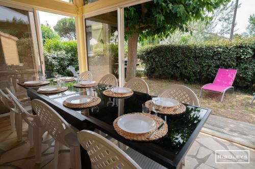 - une table noire avec des plaques et des chaises blanches sur la terrasse dans l'établissement Villa T4 à 450m de la plage avec climatisation, à Vias