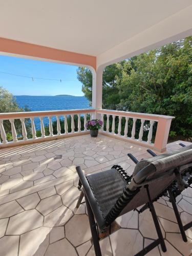 a porch with a chair and a view of the ocean at Apartments Maskovic Karbuni in Prizba