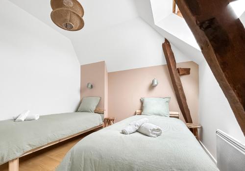 - 2 lits dans une chambre mansardée avec des murs blancs dans l'établissement Escapade paisible Proche Rennes, à Pont-Péan
