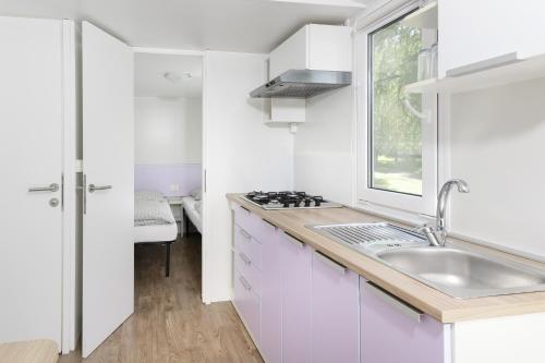 a white kitchen with a sink and a window at Camping 2000 - Stacaravan Fiji in Osečná