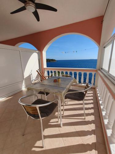 a balcony with a table and chairs and the ocean at Apartments Maskovic Karbuni in Prizba