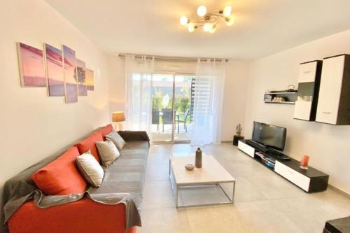 un salon avec un canapé rouge et une télévision dans l'établissement Beautiful apartment for 5 with swimming pool, à Saint-Raphaël