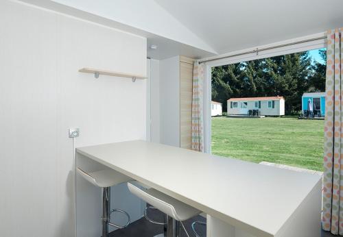 a kitchen with a white counter and a window at Camping 2000 - Stacaravan Bali in Osečná