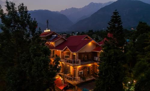 a large house with a red roof in the mountains at SaffronStays The Divine Hima in Dharamshala