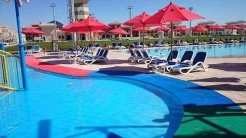 a swimming pool with chairs and red umbrellas at Elegant Apartments & Aquapark - B&B- FREE WI-FI-Sharm El Sheikh in Sharm El Sheikh