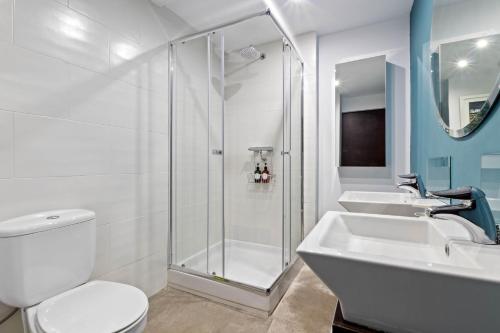 a white bathroom with two sinks and a shower at Casa Sol - Impresionantes vistas al mar in Torremolinos