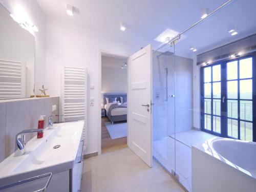 ein weißes Badezimmer mit Badewanne und Waschbecken in der Unterkunft Reetland am Meer - LuxusPlus Reetdachvilla mit 4 Schlafzimmern, Sauna und Kamin G13 in Dranske