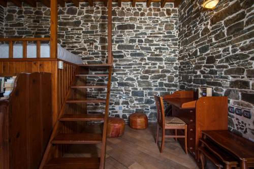 a room with a wooden staircase and a brick wall at Echo Traditional House - Ηχώ Παραδοσιακό Σπίτι in Émbonas