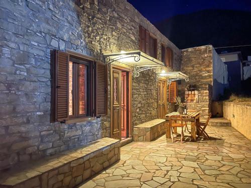 a stone building with a table in front of it at night at Echo Traditional House - Ηχώ Παραδοσιακό Σπίτι in Émbonas