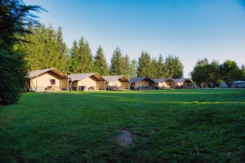 a row of lodges in a field of grass at Camping 2000 - Sahara tent XXL in Osečná
