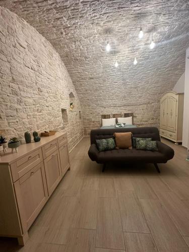 a living room with a couch and a brick wall at Antica Roma 122 in Sammichele di Bari