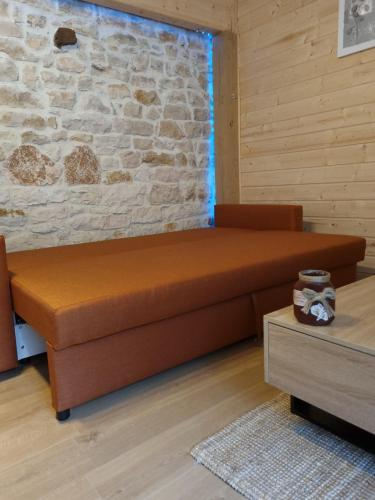 - un canapé brun dans une chambre dotée d'un mur en pierre dans l'établissement Quincey Village House, à Quincey