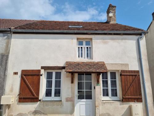 a white house with wooden doors and a roof at Quincey Village House in Quincey