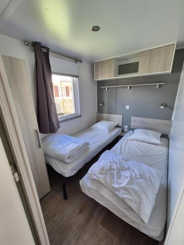 une petite chambre avec deux lits et une fenêtre dans l'établissement Le cessonnais, à Cessenon