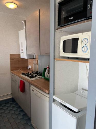 une petite cuisine avec un micro-ondes et une cuisinière dans l'établissement Au couchant logement pour 4 personnes N70, à La Grande Motte