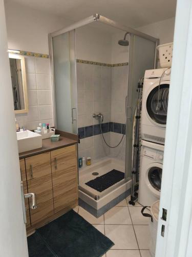 une salle de bain avec douche et machine à laver dans l'établissement Au centre ville, appartement t4 climatisé avec parking N72, à La Grande Motte