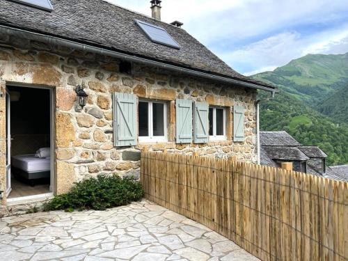 a stone house with a wooden fence in front of it at Loustalot in Aydius