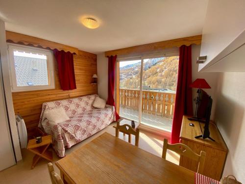 un salon avec un canapé et une grande fenêtre dans l'établissement T2 view, skiing, summer pool Balcons du Soleil, à Allos