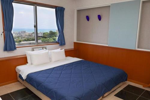 a bedroom with a bed with blue sheets and windows at HOTEL PACIFIC VIEW Rental car included & pet-friendly in Okinawa City