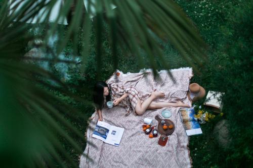 a woman laying on a picnic blanket in the grass at 阅时 Adonis野生派 Black Bar 森林大院民宿 in Lijiang