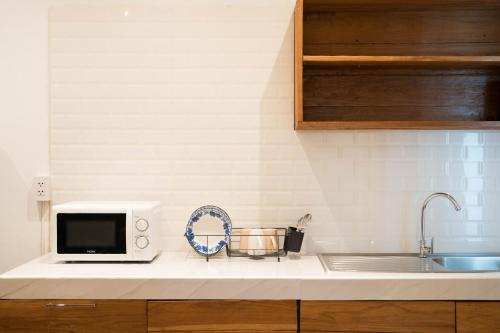 a kitchen counter with a microwave and a sink at Chiang Mai Mansion 2 in Chiang Mai