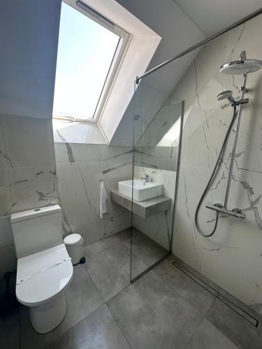 a bathroom with a toilet and a sink and a window at Студио с вана и гледка в "The House" с Термална зона in Velingrad