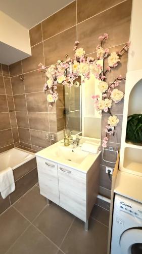 La salle de bains est pourvue d'un lavabo et d'un miroir fleuri. dans l'établissement Le Petit Bamboo - Metz, à Metz