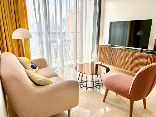 a living room with a couch and a tv and a table at 1BR condo with Amazing KLCC View & Infinity Pool at Lalaport Bukit Bintang in Kuala Lumpur
