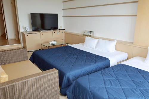 a hotel room with two beds and a flat screen tv at HOTEL PACIFIC VIEW Rental car included & pet-friendly in Okinawa City