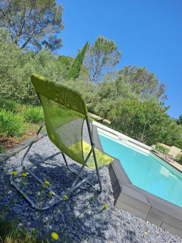 une chaise verte assise à côté de la piscine dans l'établissement Vue imprenable sur les oliviers!, à Langlade