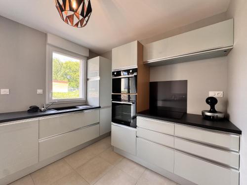 une cuisine avec des armoires blanches et une fenêtre dans l'établissement L'Art-Monie - Circuit des 24H - Parking - 6p, à Saint-Mars-dʼOutillé