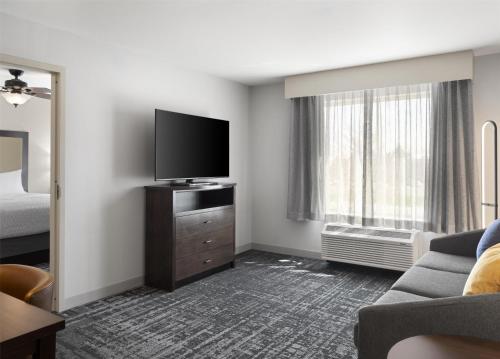 a hotel room with a flat screen tv and a couch at Homewood Suites by Hilton Akron/Fairlawn in Akron