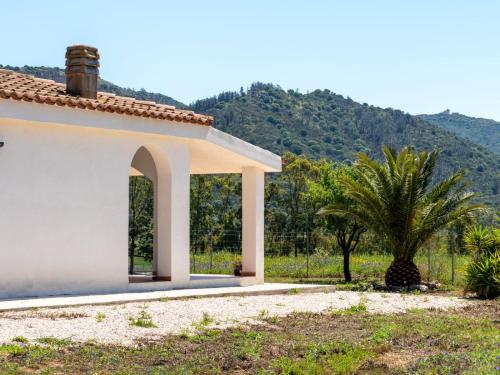 una casa blanca con una palmera y una montaña en Elisabeth's House, en Villaputzu