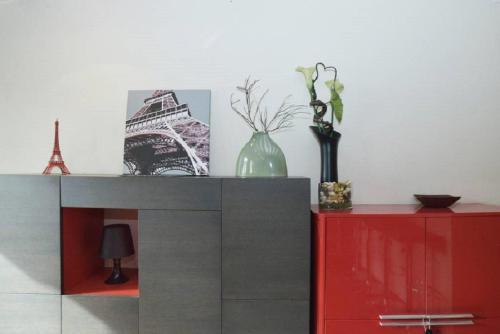 une table avec une armoire rouge et des vases dessus dans l'établissement Le Reflet du Temps, à Paris