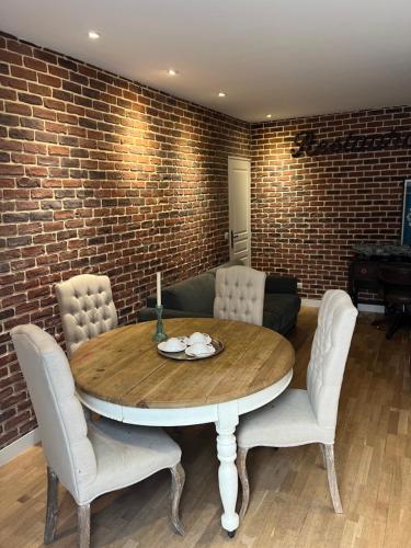 une table à manger avec des chaises et un mur en briques dans l'établissement Sara House, à Paris