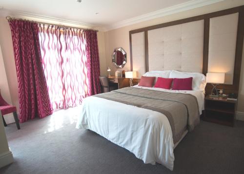 a bedroom with a large bed with red curtains at Lensfield Hotel in Cambridge