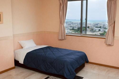 a bedroom with a bed with a view of a city at HOTEL PACIFIC VIEW Rental car included & pet-friendly in Okinawa City