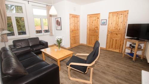 a living room with a leather couch and a table at Ferienwohnung Forsthaus am Brocken, 60 qm, 3 Schlafzimmer F5 in Ilsenburg