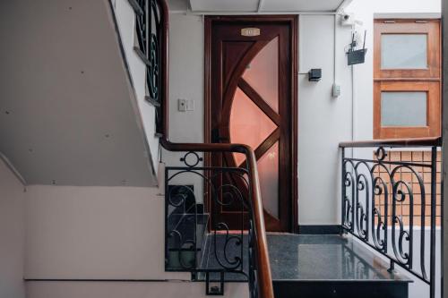 a staircase leading to a wooden door with a metal railing at Mustang 11-11 Boutique Hotel Self Check In in Ho Chi Minh City