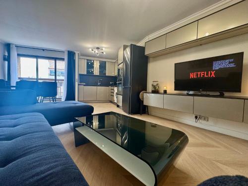 un salon avec un canapé bleu et une télévision dans l'établissement Le Suquetan By SCLS Locations, à Cannes