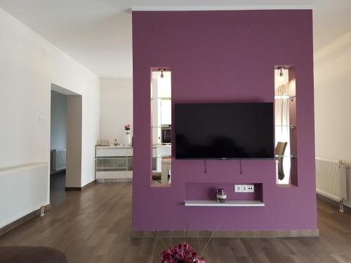 a living room with a purple wall with a tv at Apartments Tereza in Senj