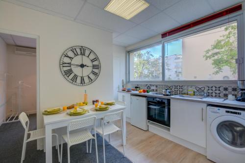 une cuisine avec une table et une horloge au mur dans l'établissement Castel du Port - Happy Rentals, à Saint-Laurent-du-Var